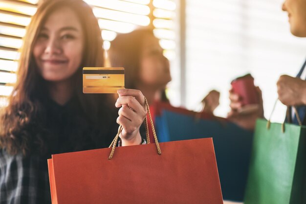 Foto donne con una borsa della spesa e una carta di credito in piedi contro la finestra