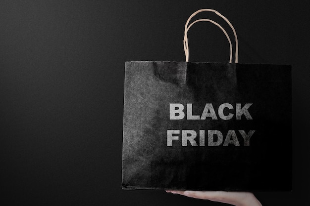 Photo women holding a shopping bag with a black background. black friday concept