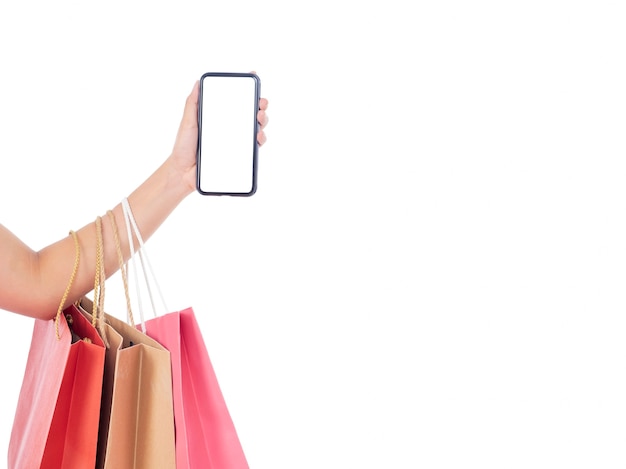 Women holding smartphone with blank screen and shopping bags on white wall