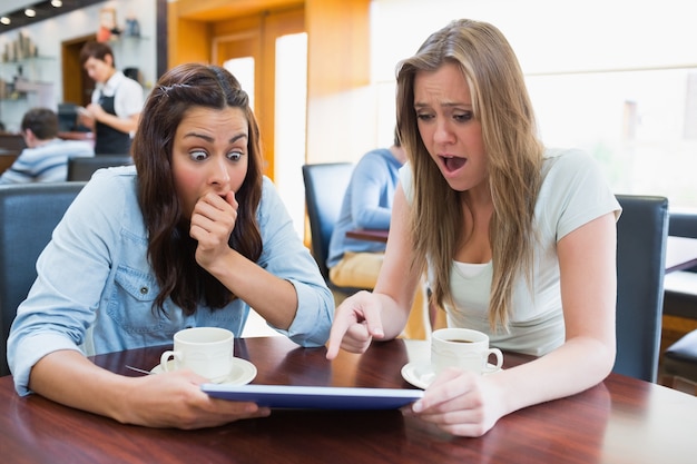 Women holding a tablet and looking surprised