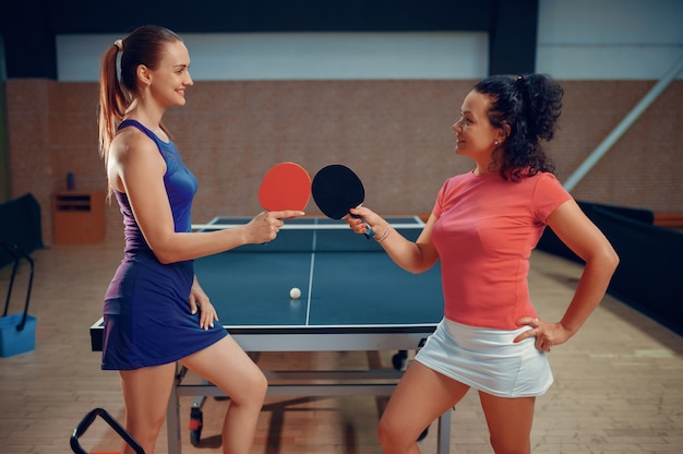 Le donne tengono racchette da ping pong