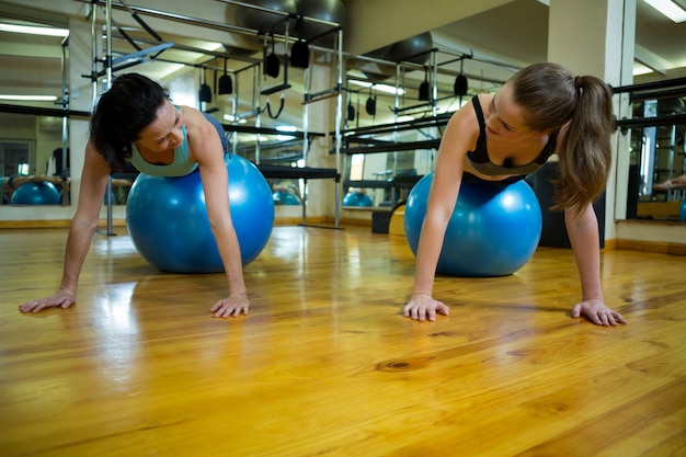 Women interacting while exercising on fitness ball