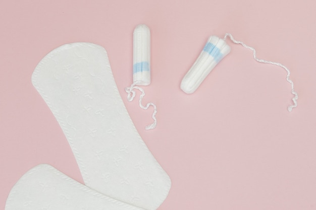 Women intimate hygiene products - sanitary pads and tampons on pink background, copy space. Menstrual period concept.