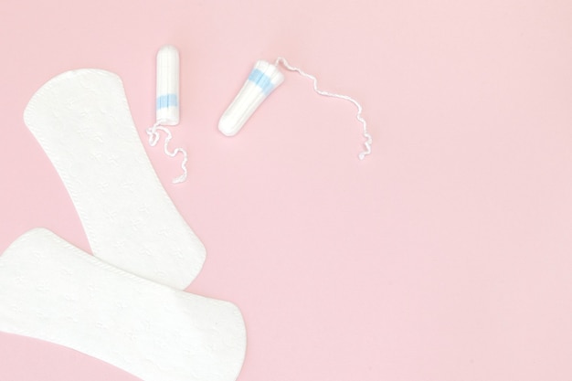 women intimate hygiene products - sanitary pads and tampons on pink background, copy space.