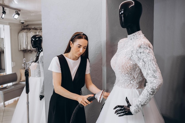다림질 기계로 스튜디오에서 웨딩 드레스를 다림질하는 여성 웨딩 컨셉