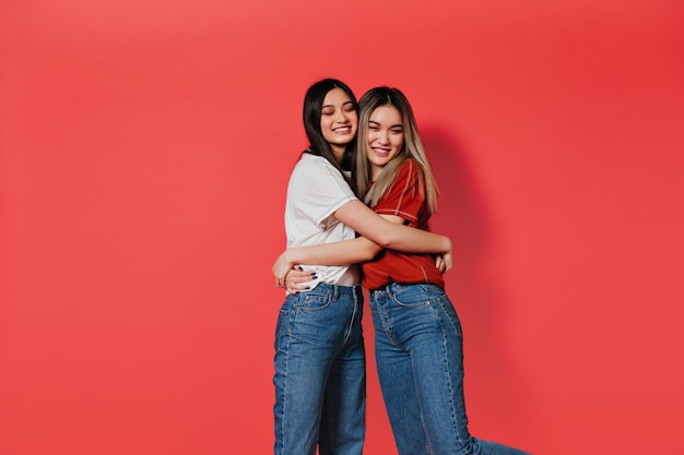 Women in jeans and tshirts hugging on isolated background