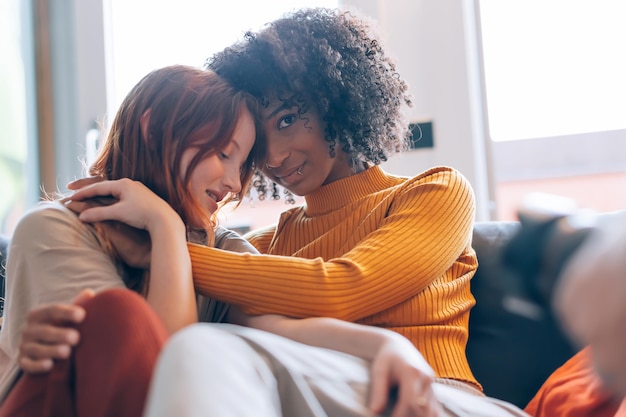 Women lesbian couple in backlight hugging on the sofa