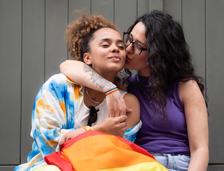 Photo women lesbian lovers are hugging and kissing they wear a rainbow flag and bracelet