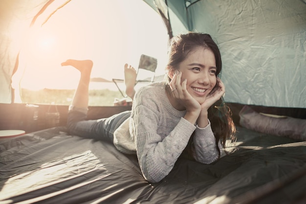 女性はキャンプでテントに横たわっています。