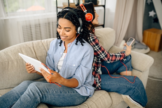 Photo women listening to music sitting back to back