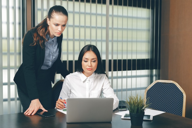 Women looking financial documents in laptop at table