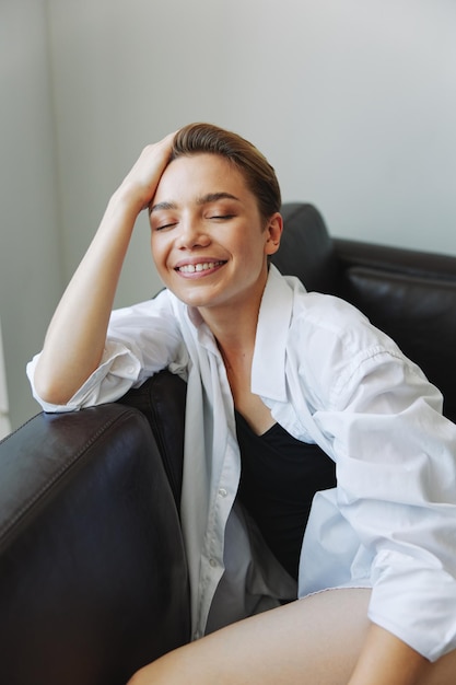 Women lying at home on the couch portrait with a short haircut in a white shirt smile depression in teenagers home holiday