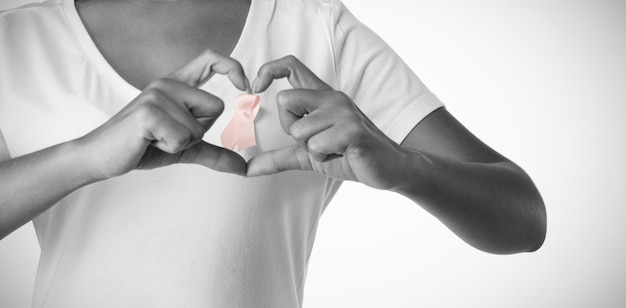 Women making heart shape with their fingers around pink ribbon