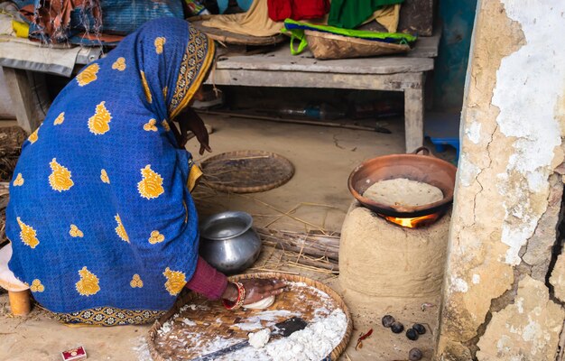 Women making rice bread in traditional soil vessels at wood fire from different angle at village