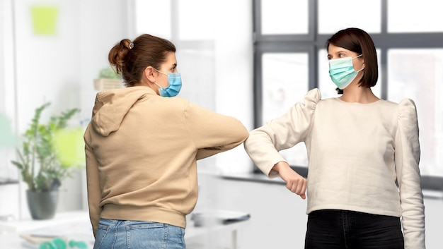 women in masks making elbow bump greeting gesture