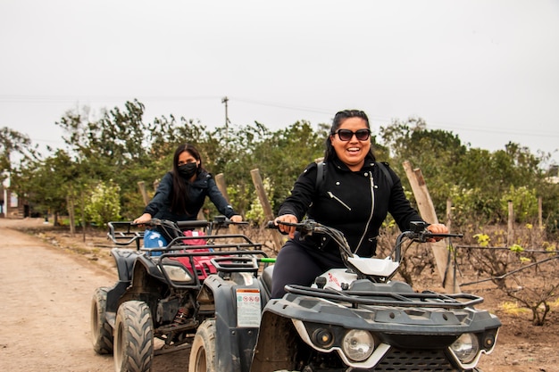 Foto donne e uomini su atv si stanno godendo un giro in un campo