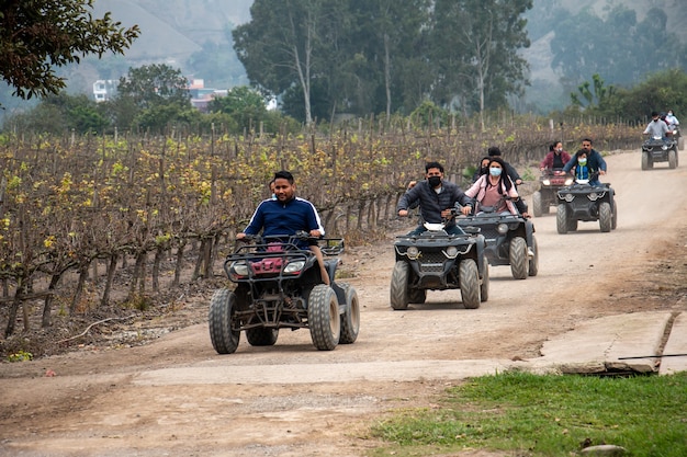 Women and men on ATVs are enjoying a ride in a field