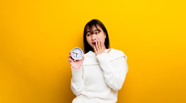 Donne e uomini hanno tempo persone che sono puntuali al lavoro donna in possesso di un orologio che dice l'ora dell'orologio di piantagione bianco su sfondo giallo