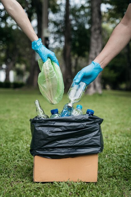 Foto donne e uomini conservano le bottiglie di plastica dei rifiuti in sacchi neri al parco alla luce del mattino