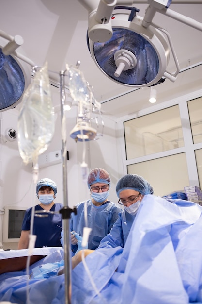 Women on the operating table perform operations on varicose veins of the legs