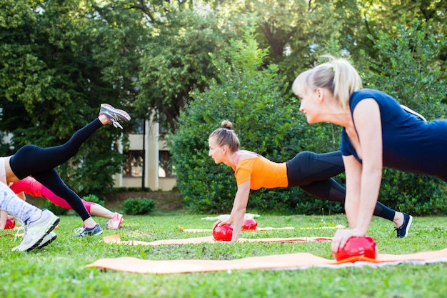 Women in the park are doing exercise with fitness balls. Power training outdoor