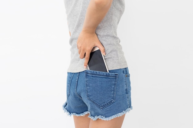 Le donne prendono il telefono nella tasca posteriore di jeans su sfondo bianco