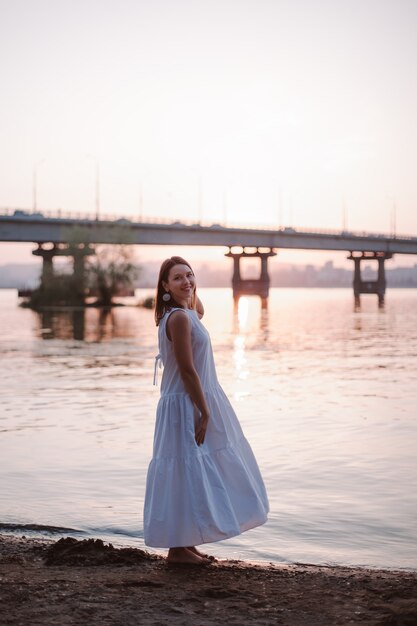 Women posing at sunset fulllength portrait of a beautiful young woman posing at sunset on the beach ...