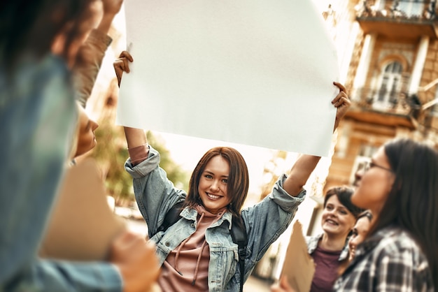 여자는 그녀의 머리 위에 빈 간판을 들고 웃 고 행복 한 젊은 여자 전원