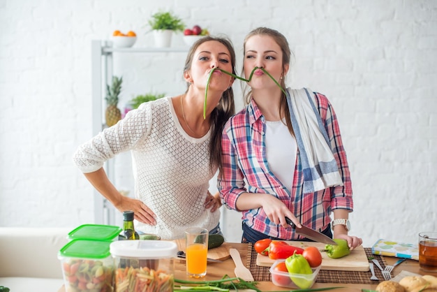 Фото Женщины готовят здоровую пищу, играя с овощами на кухне, развлекаясь концепцией диетического питания