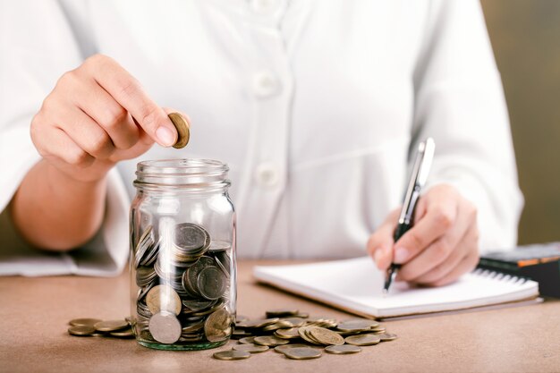 Women putting coin in glass bottle saving bank and a finance accounting