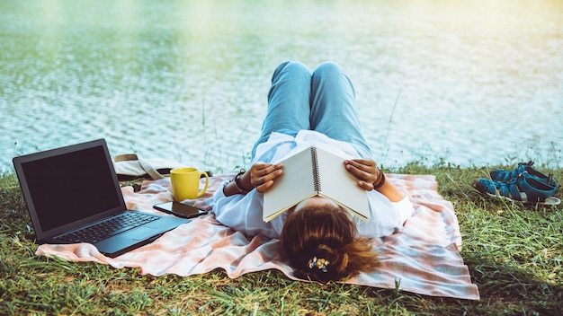 Photo women reading next to the river