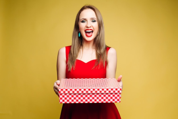 Women in red dress smiling and holding present for new year.