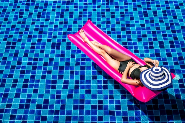 A women relaxing and lying on pink inflatable mattresses.