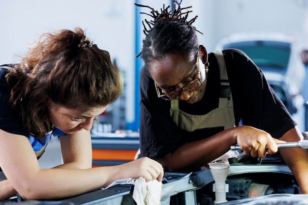 Photo women in repair shop working to fix car