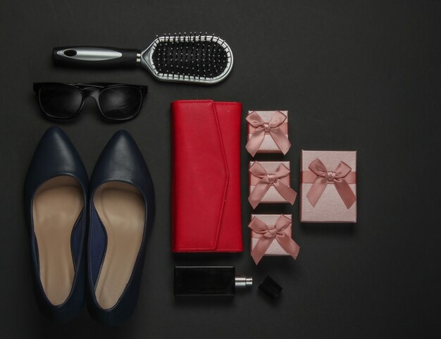 Photo women's accessories on a black background. high heel shoes, comb, sunglasses, perfume bottle, purse, gift box. birthday, mother's day, christmas. top view