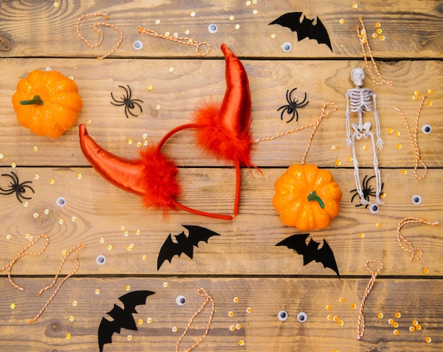 Accessori da donna per una festa di halloween una fascia piatta con corna da diavolo scheletro di zucca ragni e pipistrelli su fondo in legno un tema festivo di halloween