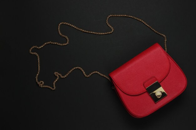 Women's accessories. Leather red bag on a black background. Top view