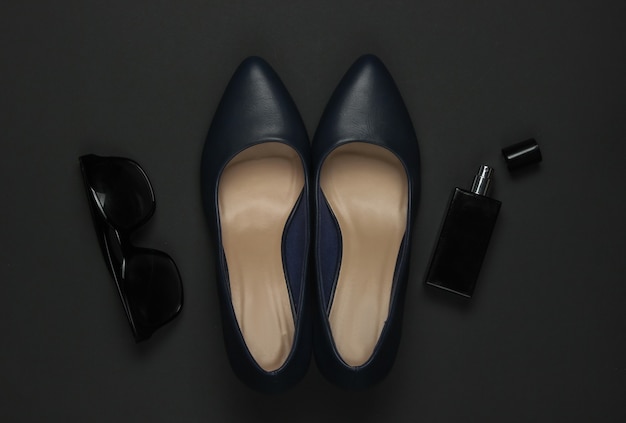 Фото Женские аксессуары на черном фоне. туфли на каблуках, флакон духов, солнцезащитные очки. вид сверху