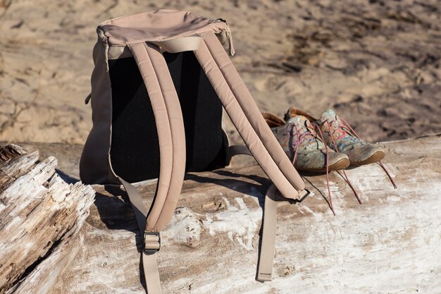 women's backpack and sneakers are on a log