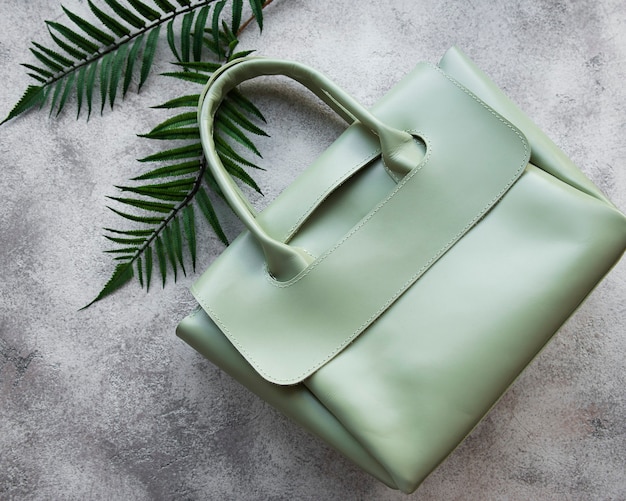 Women's bag made of green leather on a gray concrete background