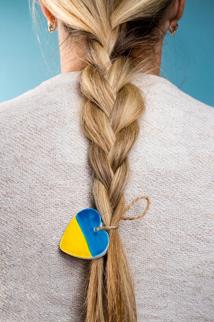 Foto treccia da donna con cuore nei colori patriottici della bandiera ucraina giallo e blu ferma la guerra in ucraina aiuta a salvare la nazione ucraina