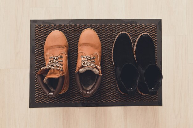 Women's Brown Suede And Black Boots On A Mud Mat In The Hallway