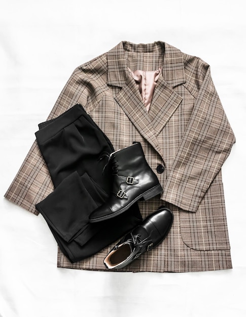 Women's clothing plaid jacket black trousers and leather shoes on a light background top view