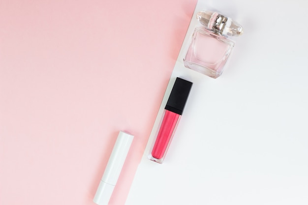 Women's cosmetics on a pink white background. Lipstick and perfume, beauty and fashion concept. Top view, flat lay, copy space, minimalist concept.