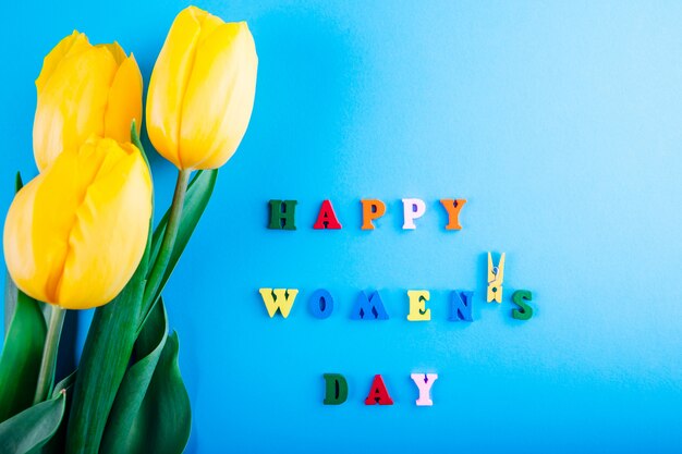 Photo women's day lettering with yellow tulips