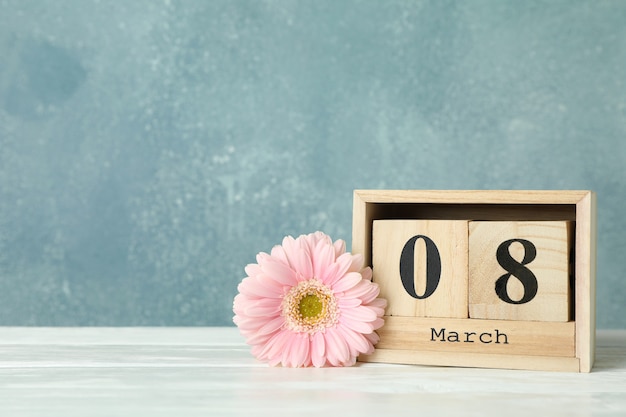 写真 女性の日3月8日、木製ブロックカレンダー。母の日おめでとう。白いテーブルの春の花。テキストのためのスペース