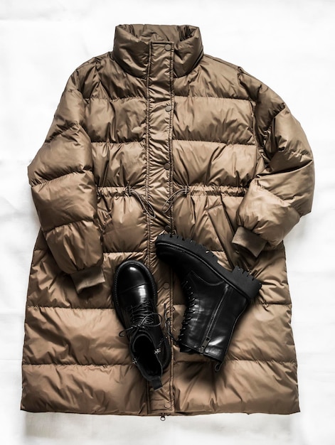 Women's down jacket and black leather massive laceup boots on a light background Top view
