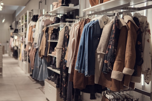 Women's dresses and jacket on hangers in a retail shop. Fashion and shopping concept