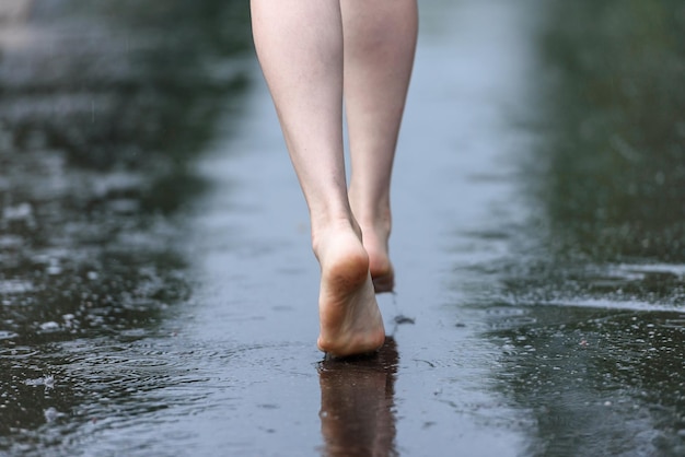 Foto eleganti piedi nudi di donne che camminano tra le pozzanghere