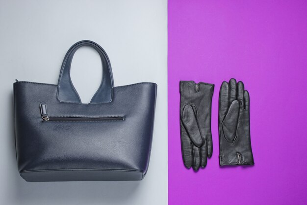 Women's fashion accessories on a gray-purple table. Leather bag, gloves. Top view